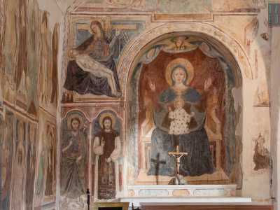 Partiamo dall�altare, dietro il quale si staglia un abside interamente decorato con la raffigurazione della Madonna col Bambino con la sua tunica blu e il manto azzurro, raffigurata in atteggiamento solenne
